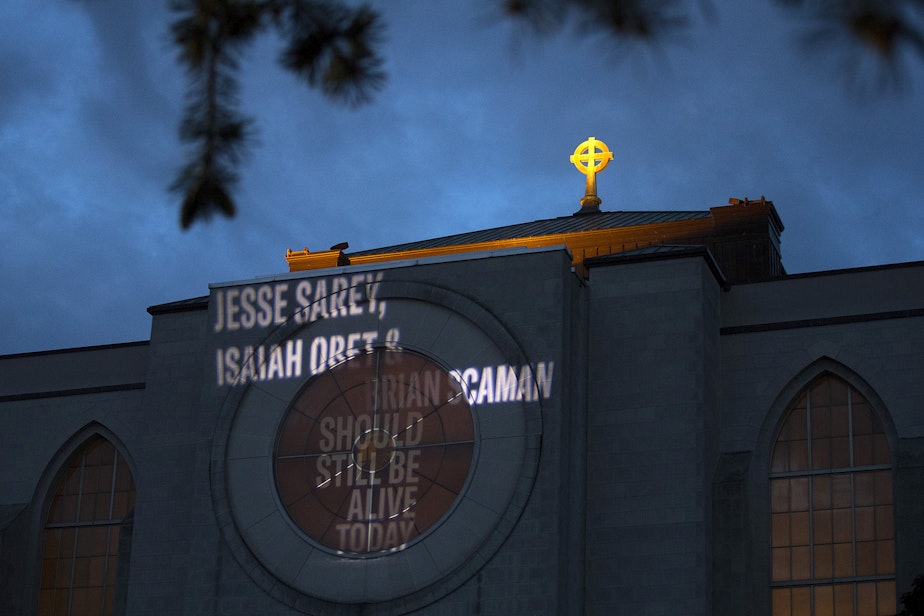 caption: 'Jesse Sarey, Isaiah Obet & Brian Scaman Should Still Be Alive Today' is shown projected onto the side of Saint Mark's Episcopal Cathedral on Thursday, June 3, 2021, in Seattle. The “Projecting Justice” project is a collaboration between the ACLU of Washington, The Washington Coalition for Police Accountability, and Saint Mark’s. On Thursday, family members of those killed by Auburn police officer Jeffrey Nelson gathered for a small vigil. 