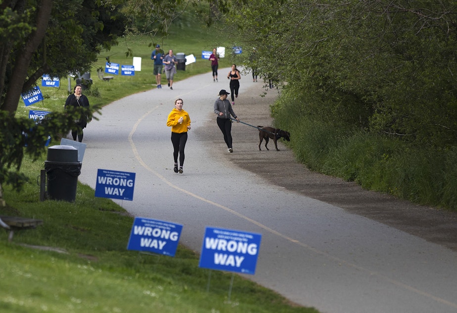 caption: People walk and jog around the perimeter of Green Lake on Monday, May 18, 2020, in Seattle.