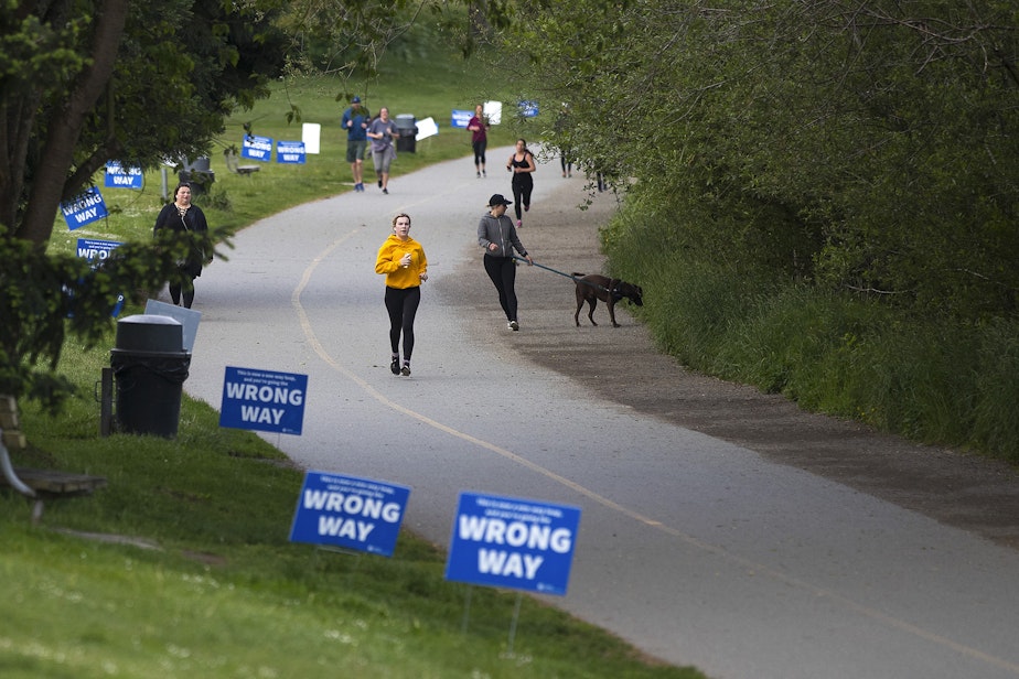 caption: People walk and jog around the perimeter of Green Lake on Monday, May 18, 2020, in Seattle. 