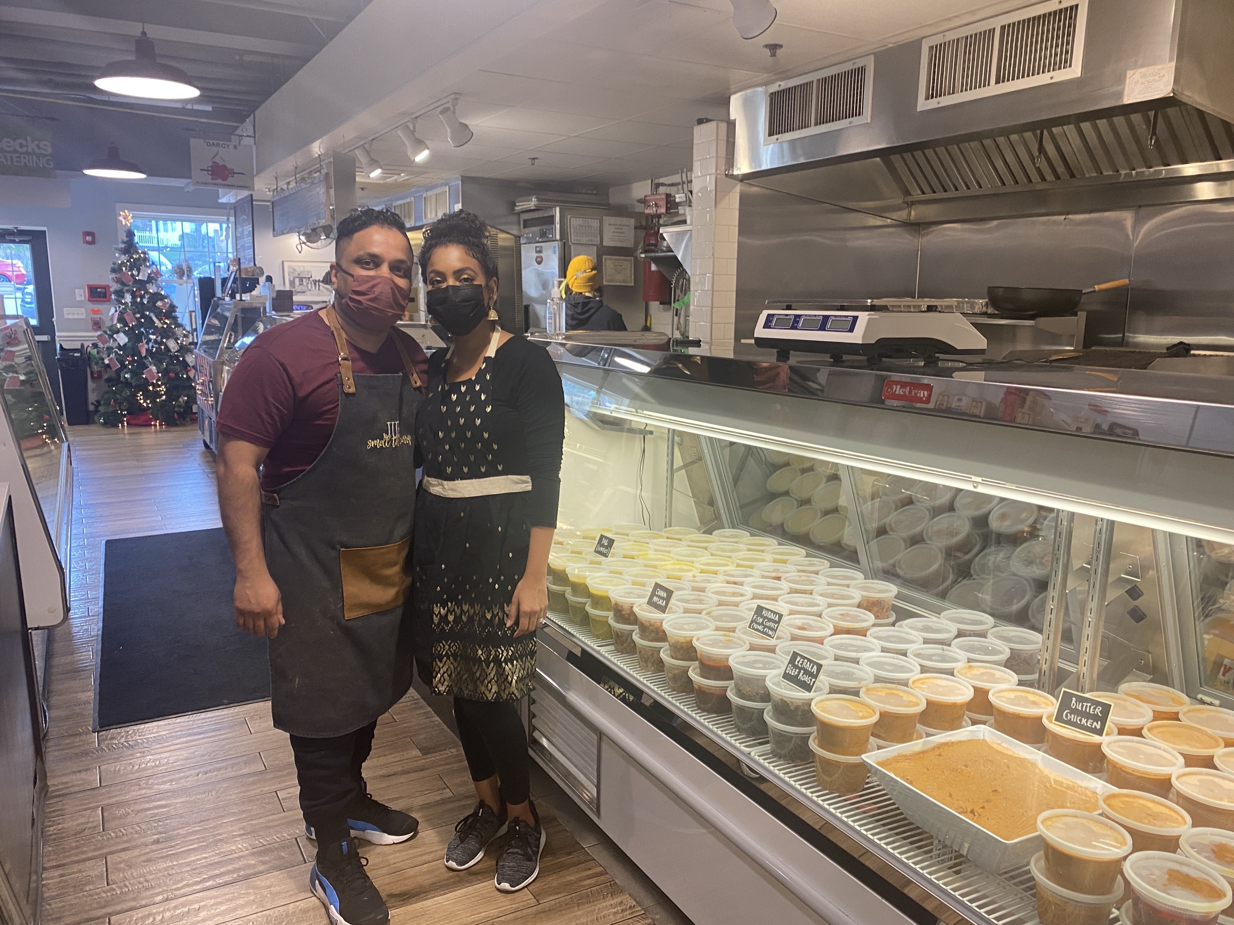caption: Juby George stands with his wife Shireen Bethala-George at the soft opening of Smell the Curry, a south Indian takeout and catering business at the Flourtown Farmers Market outside Philadelphia, on December 9, 2021.