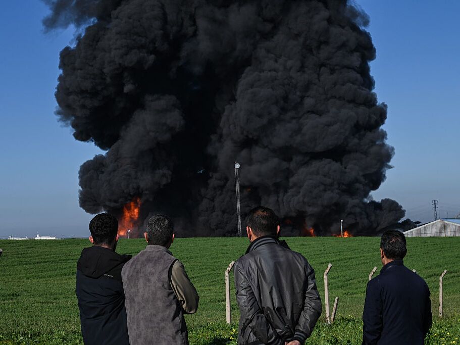 caption: People watch as smoke billows from an oil warehouse in the Kani Qirzhala area on the outskirts of Irbil, the capital of the Kurdistan region of northern Iraq, following a suspected drone strike, on Wednesday.