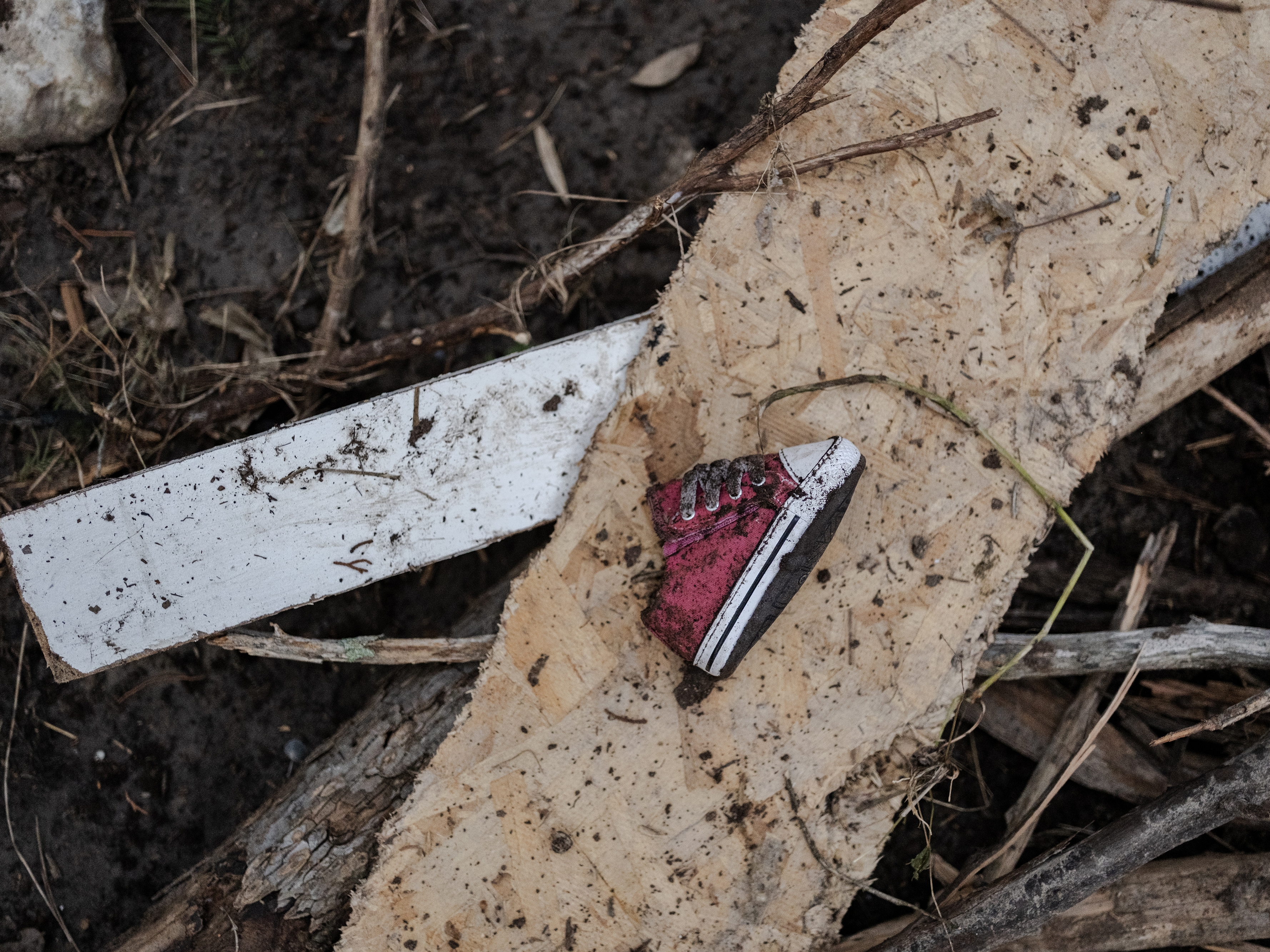 caption: A baby shoe lays along the Guadalupe River after it was swept up in the flash flooding in Ingram, Texas.