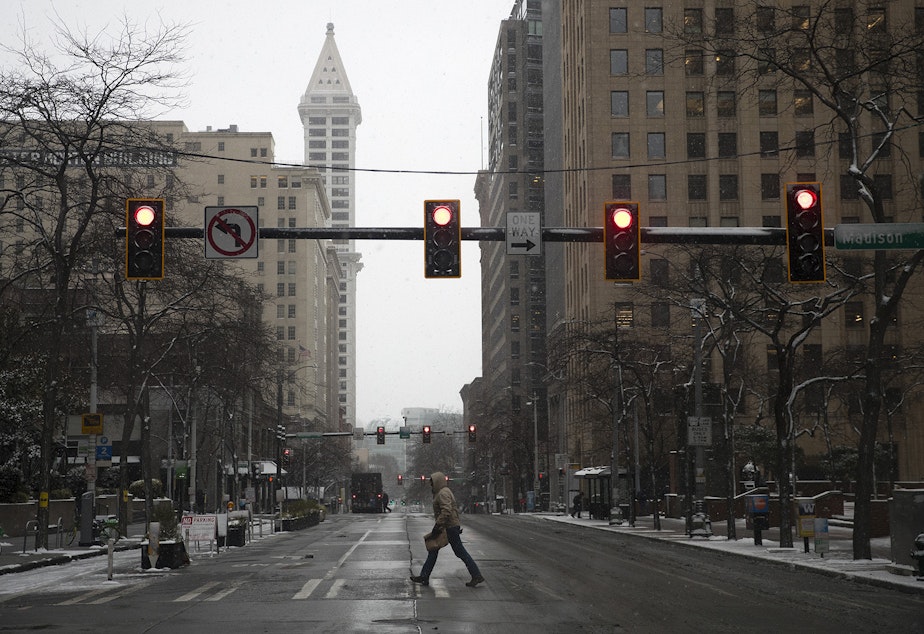 A pedestrian crosses Madison Street as snow falls on Monday, February 4, 2019, in Seattle.