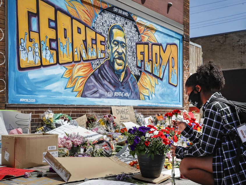 caption: Malaysia Hammond places flowers at a memorial mural for George Floyd in Minneapolis on Sunday. Police brutality has sparked days of civil unrest. But the sparks have landed in a tinderbox built over decades of economic inequality, now exacerbated by the coronavirus pandemic.