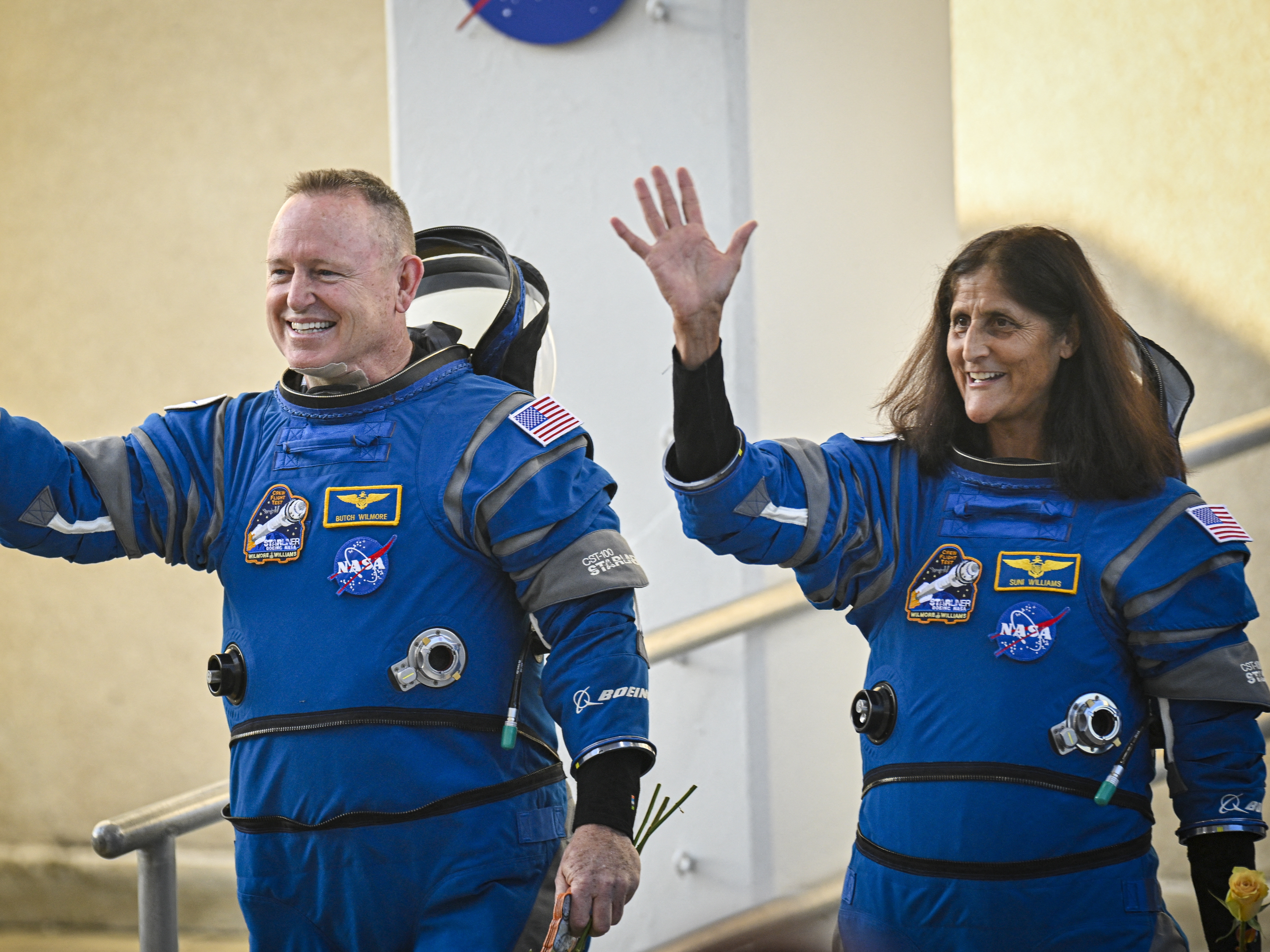 caption: NASA astronauts Butch Wilmore (L) and Suni Williams, wave as they prepare to depart the Neil A. Armstrong Operations and Checkout Building at Cape Canaveral Space Force Station in Florida to board the Boeing CST-100 Starliner spacecraft, on June 5, 2024. 