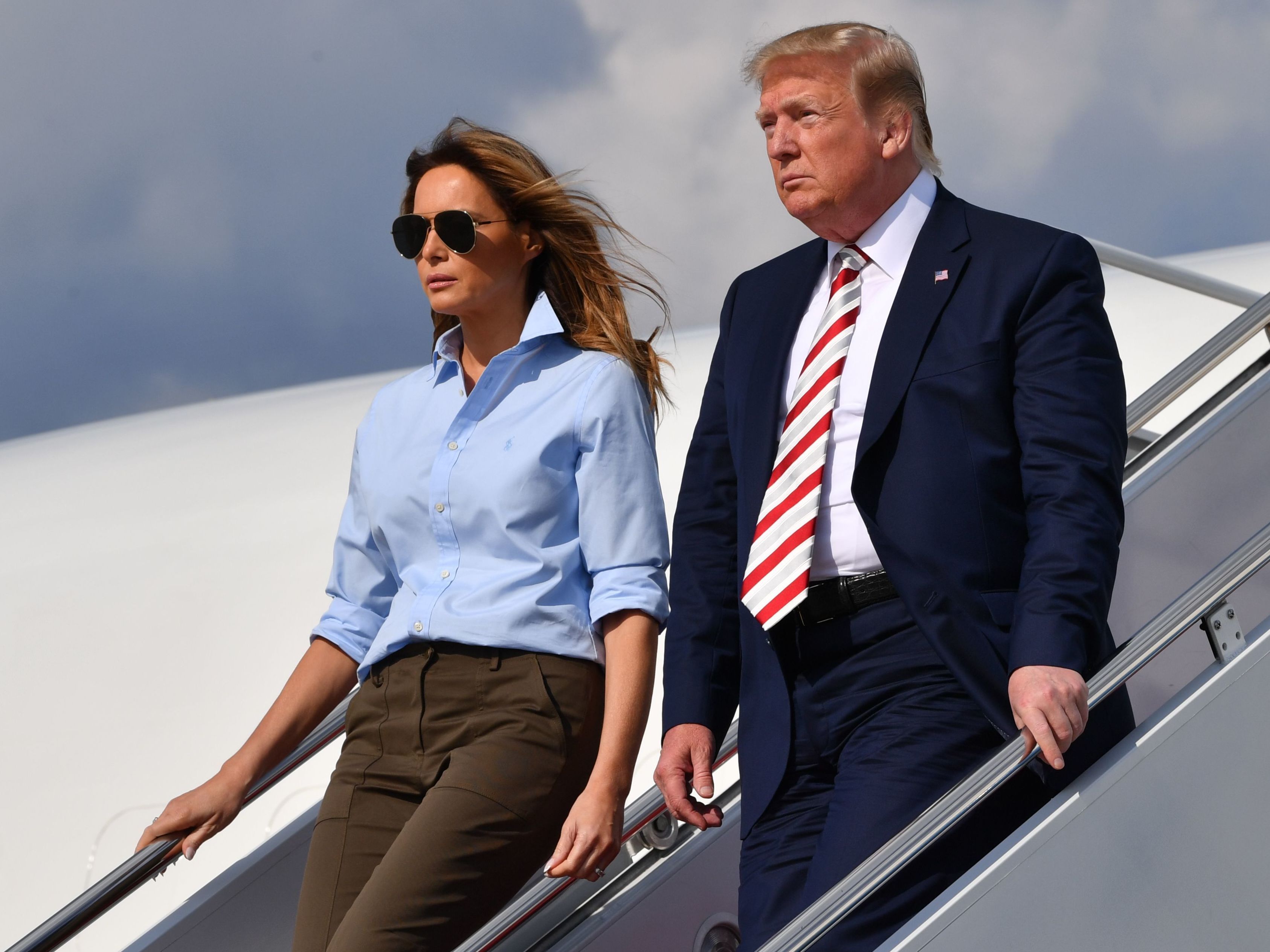 caption: President Trump disembarks Air Force One with First Lady Melania Trump, on Aug, 4, 2019 after two mass shootings over the weekend. Trump has called for "strong background checks" in response to the shootings.