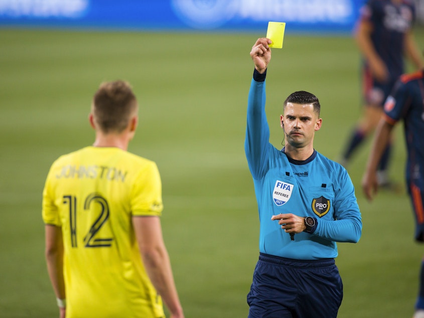 caption: Alistair Johnston of Nashville SC is issued a yellow card during the second half of a match against FC Cincinnati at Nissan Stadium on April 17, 2021 in Nashville.