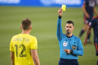 caption: Alistair Johnston of Nashville SC is issued a yellow card during the second half of a match against FC Cincinnati at Nissan Stadium on April 17, 2021 in Nashville.