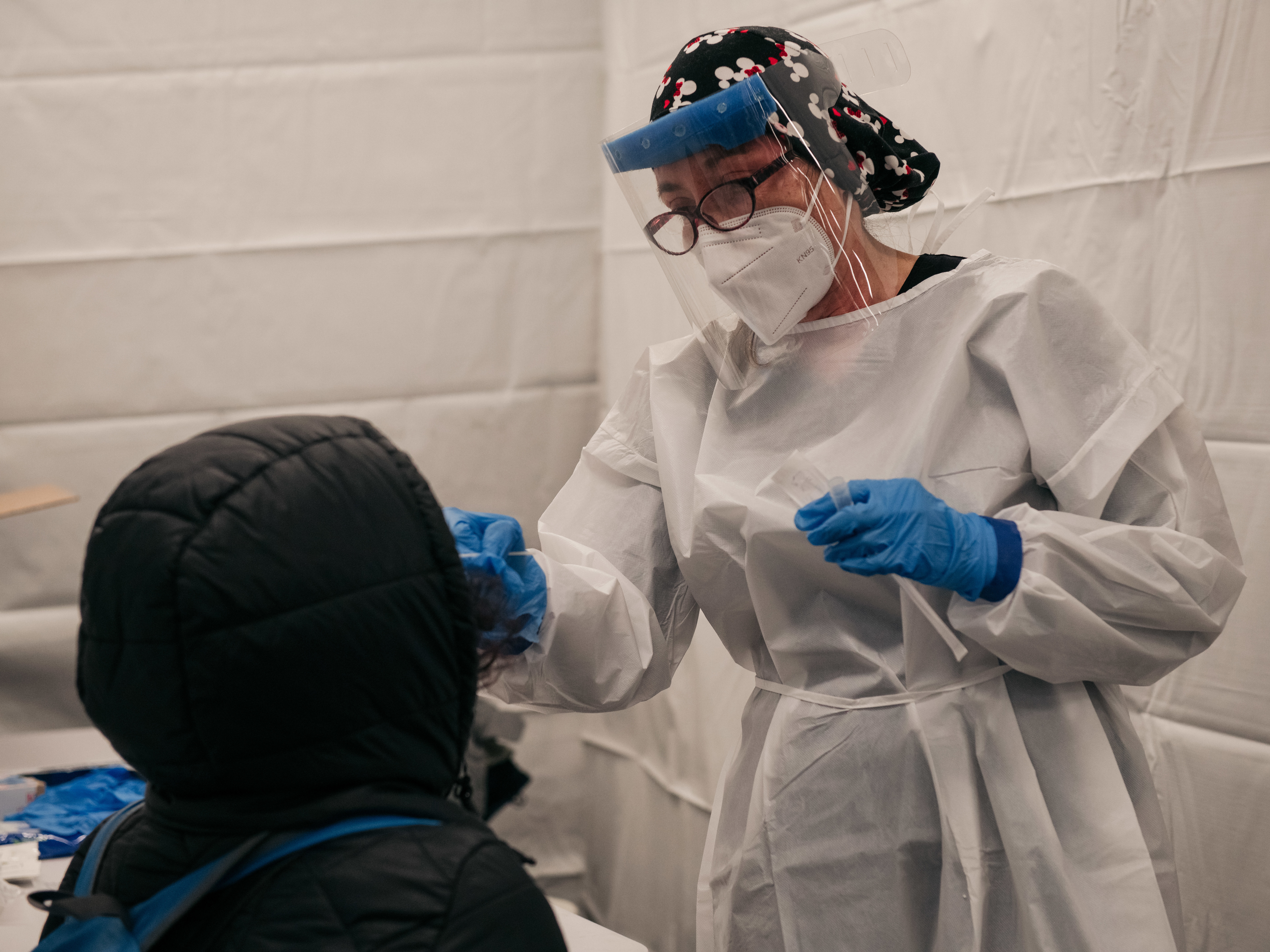 caption: A medical worker administers a COVID-19 test at a new testing site at the Times Square subway station in New York City on Monday.