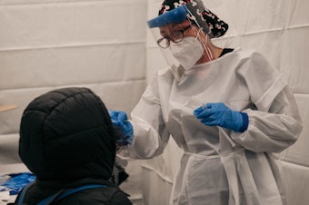 caption: A medical worker administers a COVID-19 test at a new testing site at the Times Square subway station in New York City on Monday.