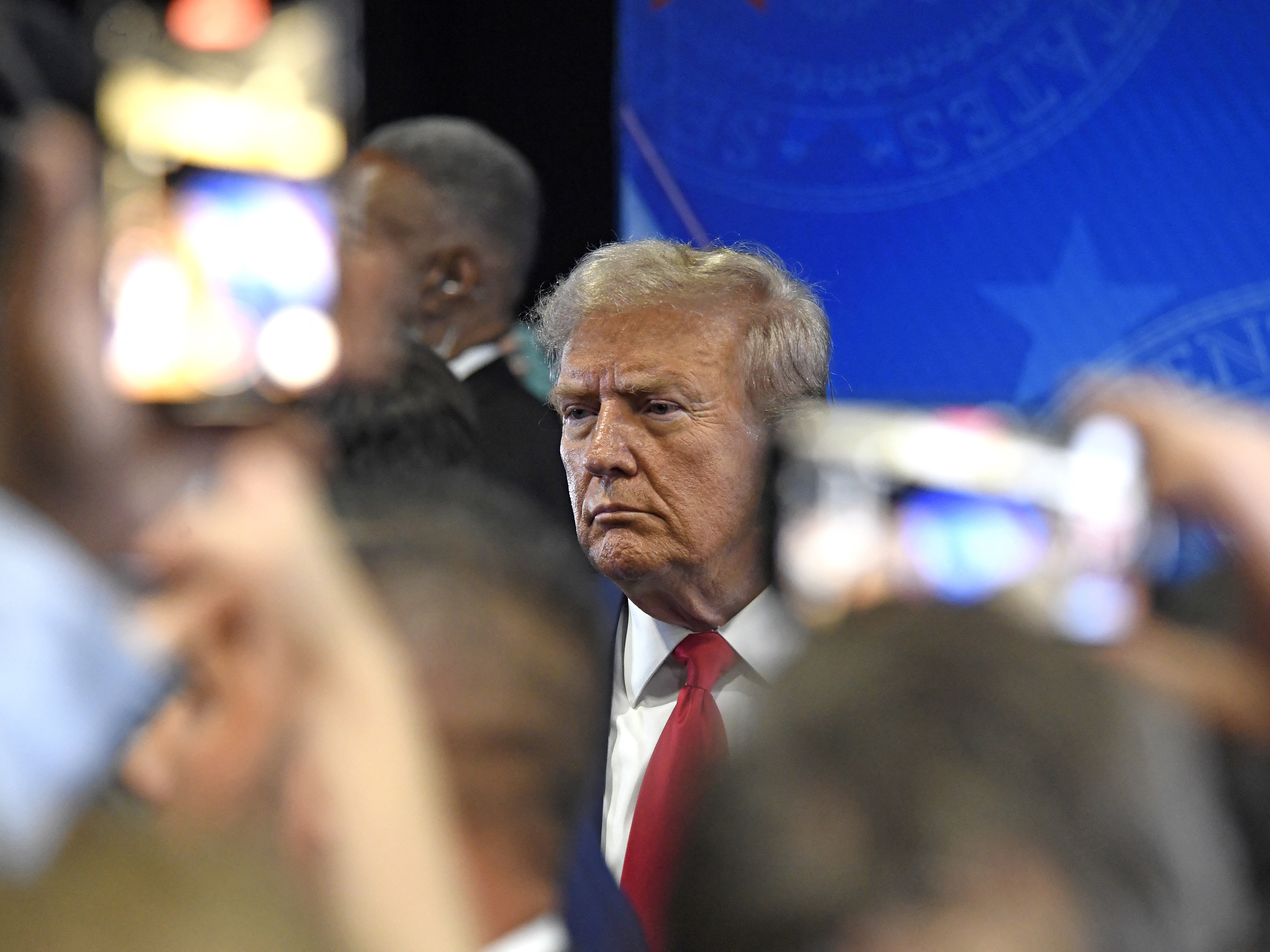 caption: Former President Donald Trump speaks to members of the press following a presidential debate with Vice President Kamala Harris. Shares in his Trump Media company plunged to a record low the morning after the debate.