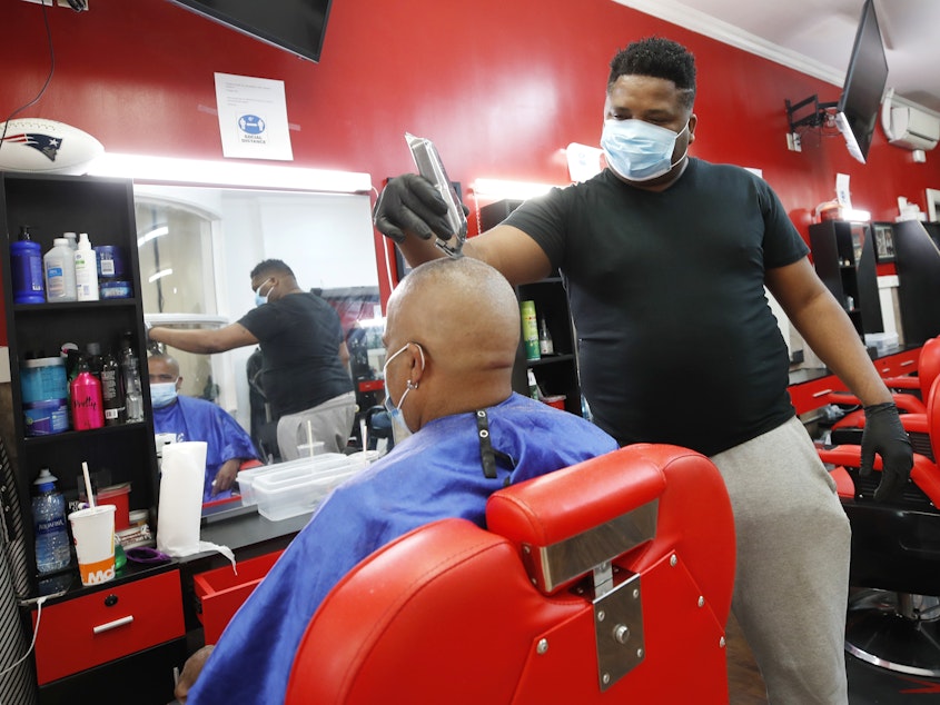caption: Wilkin Soto works on a customer at the Castillo Barbershop, in Lawrence, Mass., on June 5.