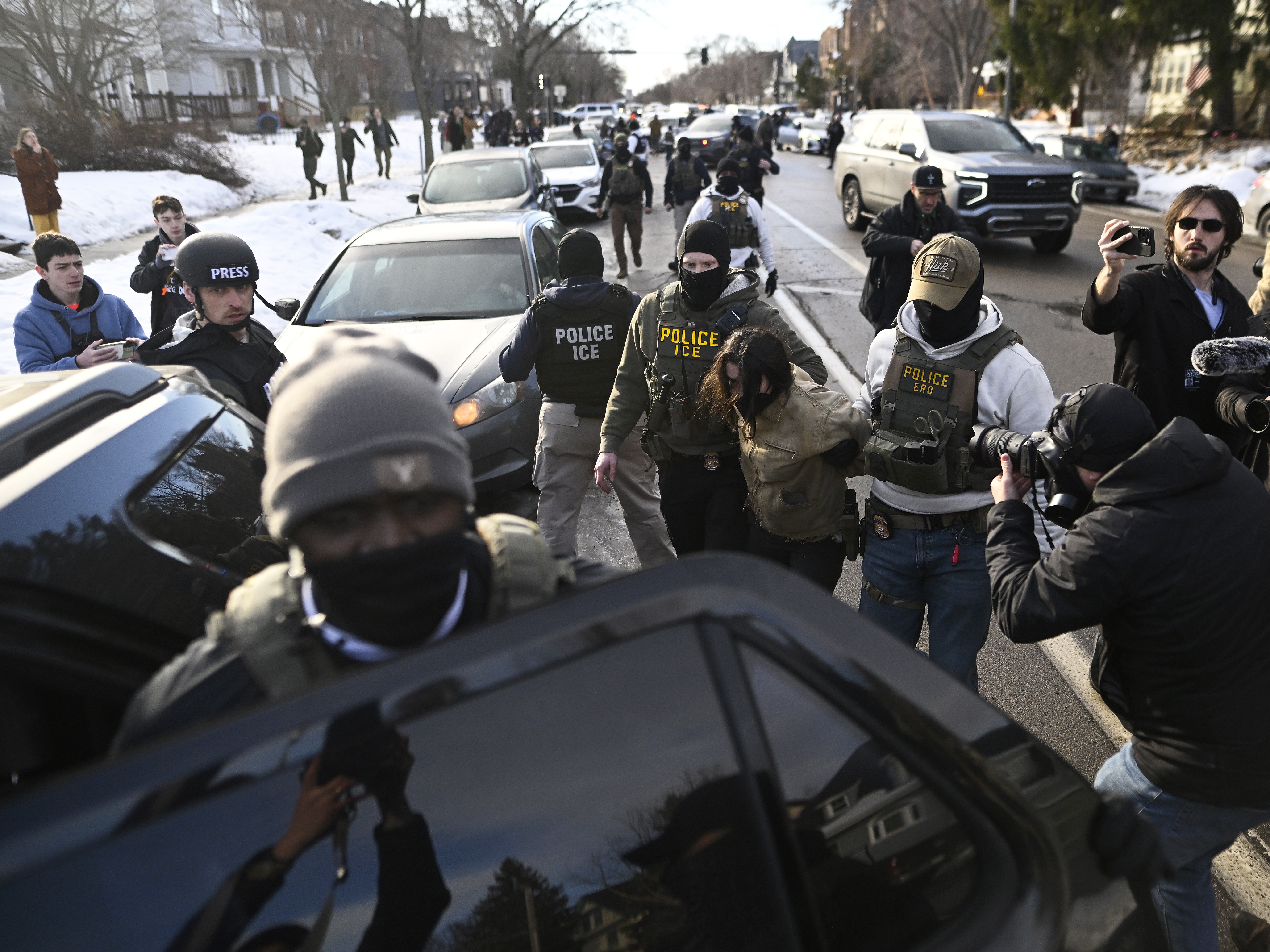 caption: An observer is detained by ICE agents after they arrested two people from a residence in Minneapolis on Jan. 13.