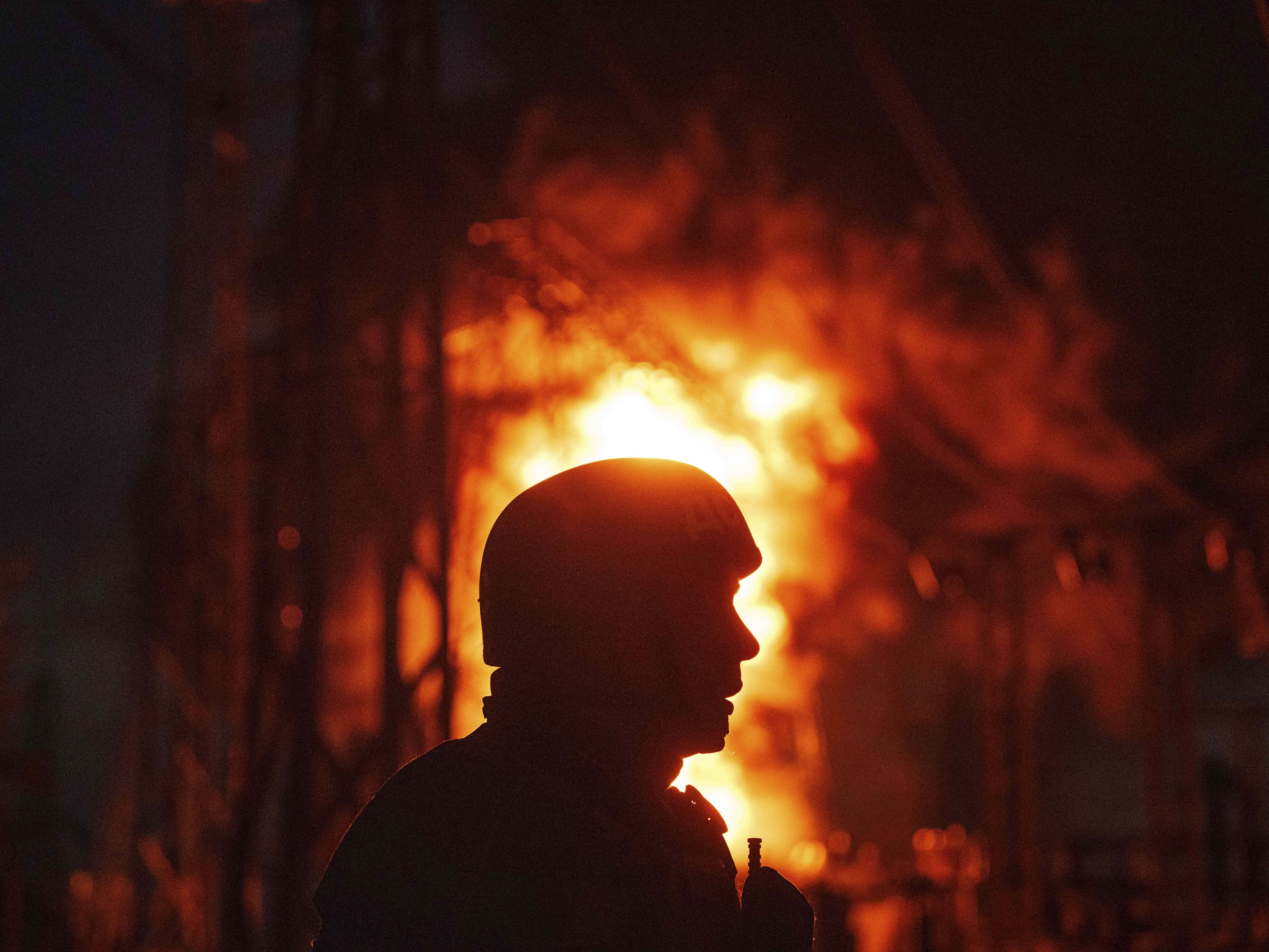 caption: A Ukrainian rescue worker looks on at a burning electrical substation hit by a Russian bomb in the Dnipropetrovsk region in eastern Ukraine on Sept. 2. 
