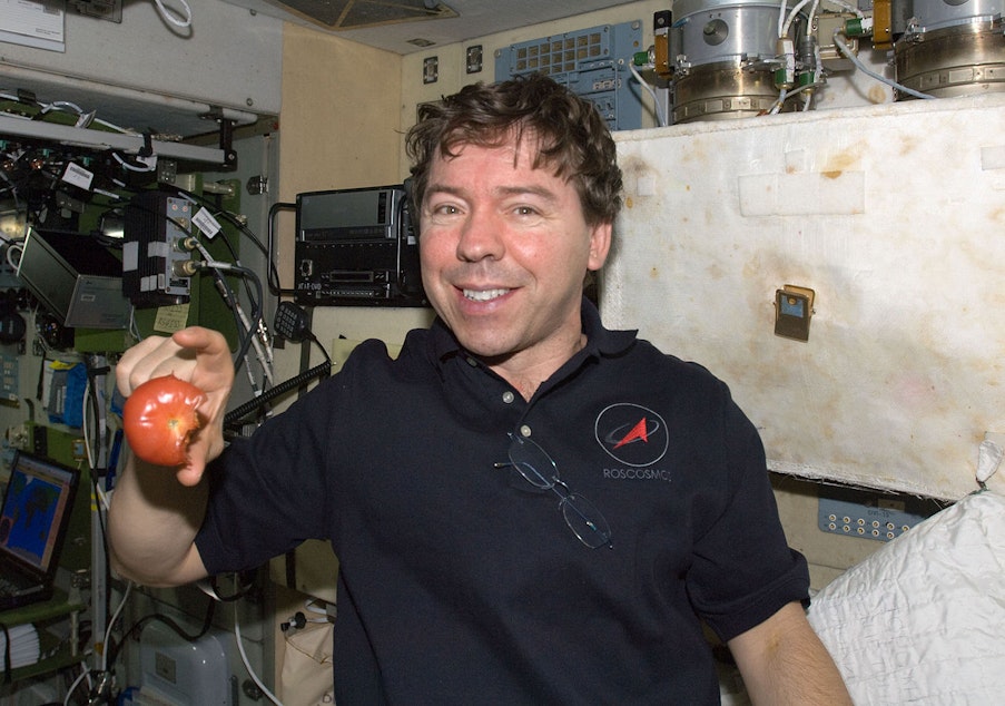 caption: NASA astronaut Michael Barratt with floating tomato in Zvezda service module of the International Space Station.