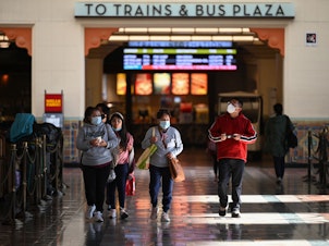 caption: A family wearing face masks walks through Union Station in Los Angeles, California, January 5, 2022. With the Omicron variant driving a surge of Covid-19 cases, California announced January 5, 2022 that a statewide indoor mask mandate, due to expire on January 15, 2022, will be extended until at least February 15, 2022.