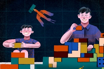 A young boy and teenage boy build blocks together.