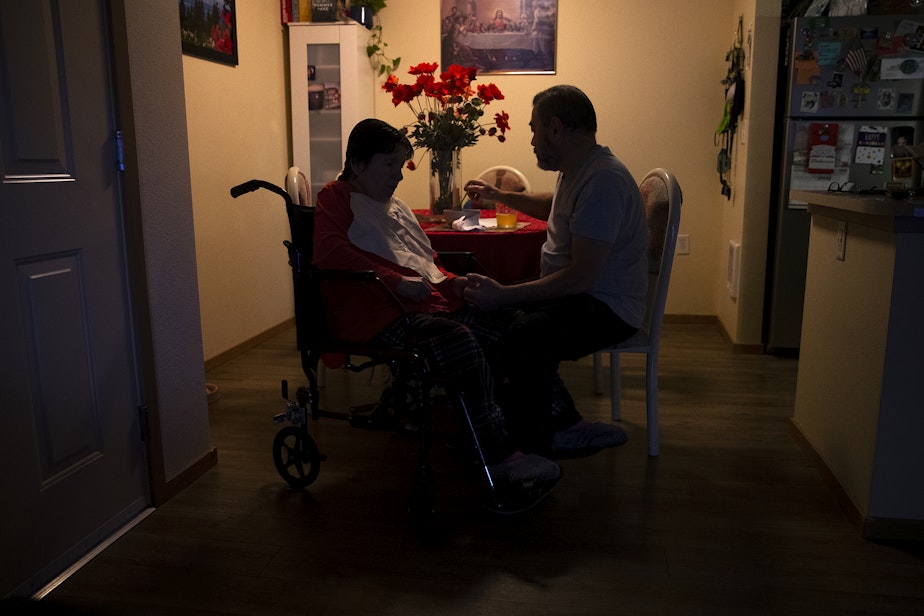 caption: Omar, right, feeds his wife Marta, left, at their apartment on Tuesday, September 26, 2023, in Everett.