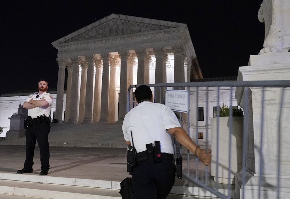 caption: Police move barricades in place as a crowd of people gather outside the Supreme Court, Monday night, May 2, 2022 in Washington.