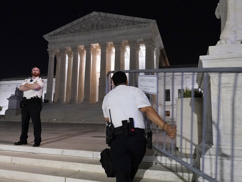 caption: Police move barricades in place as a crowd of people gather outside the Supreme Court, Monday night, May 2, 2022 in Washington.