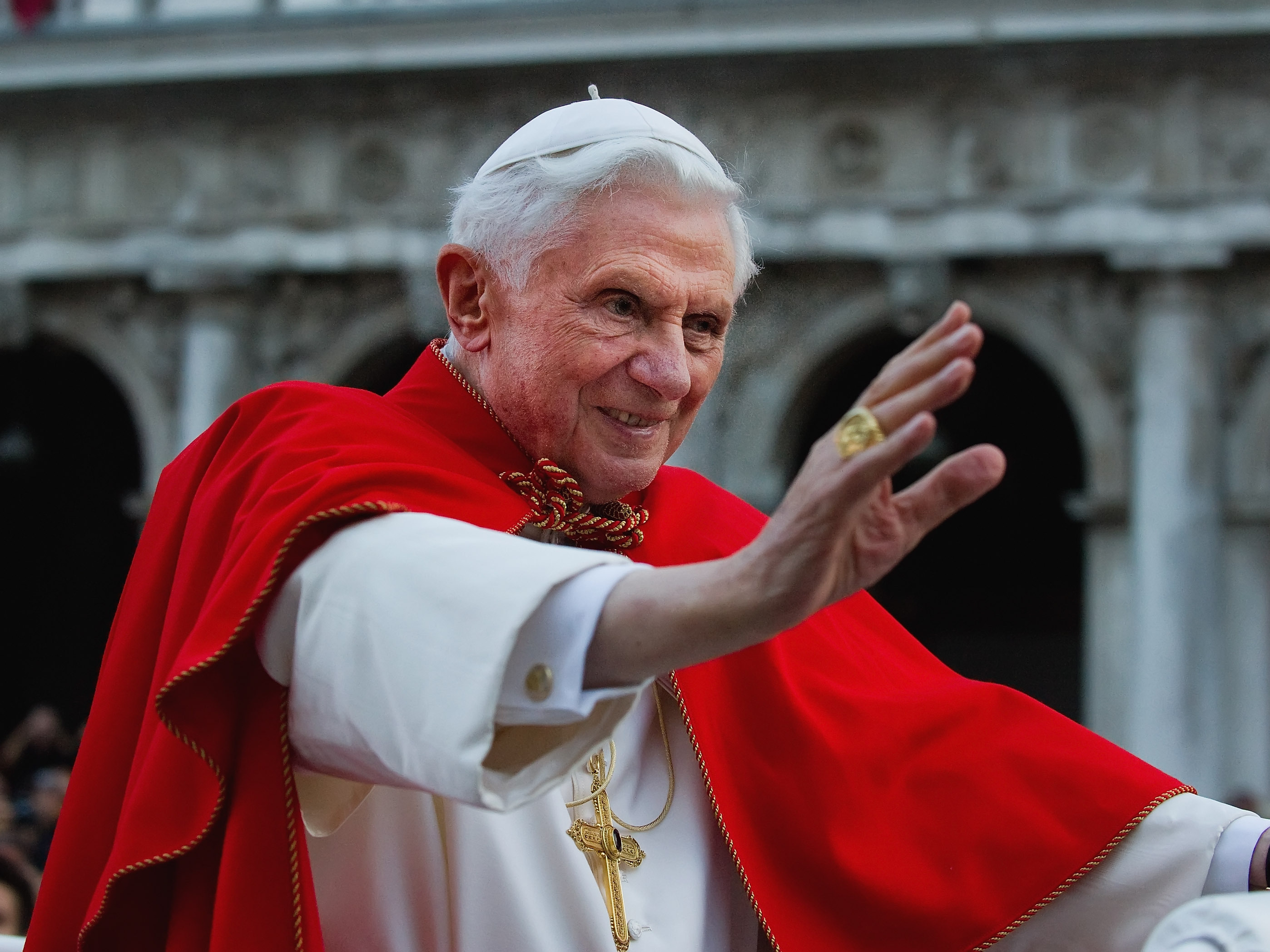 caption: Pope Benedict XVI greets the crowd gathered in St Mark's Square while crossing the square on an electric car in 2011 in Venice, Italy.