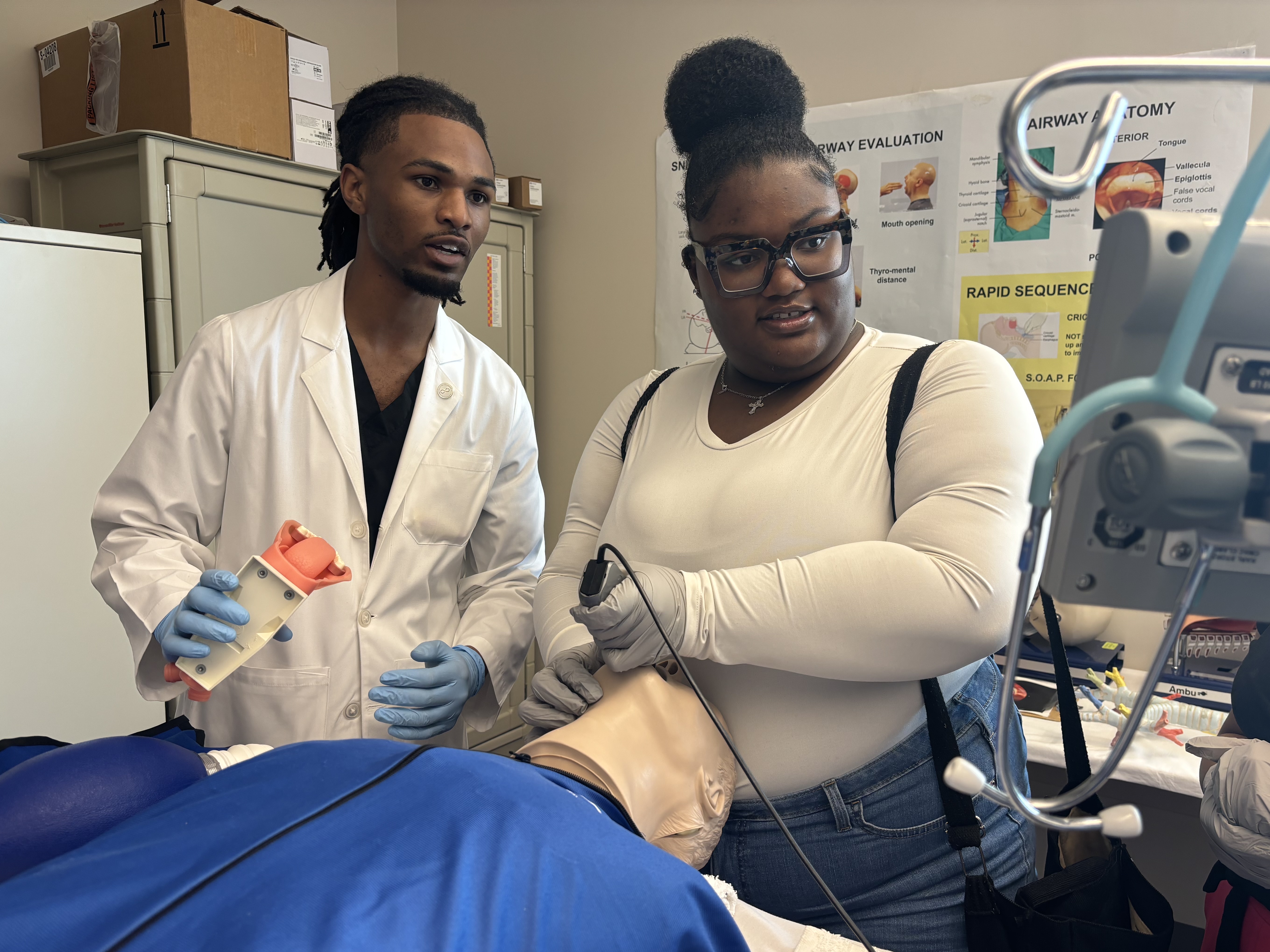 caption: Jerrian Reedy, left, a student at the University of Mississippi School of Medicine, assists Dorothy Gray, a student at Northside High School in the Mississippi Delta, as she practices intubation in a simulation lab. Gray, who is interested in pursuing a career in the mental health care field, attended the University of Mississippi School of Medicine’s annual African American Visit Day in April. 