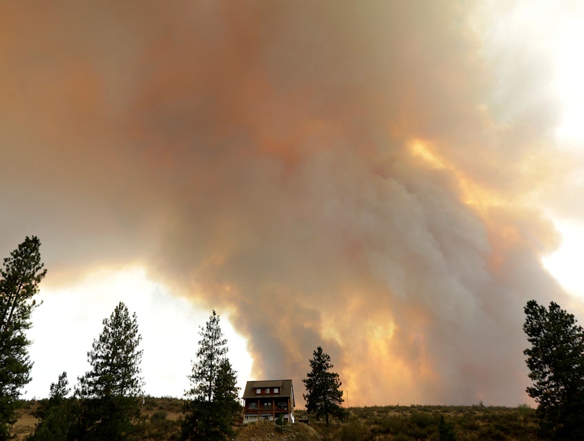 caption: Smoke from an approaching wildfire looms over a home near Twisp, Wash., Aug. 19, 2015. 