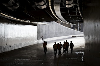 caption: Members of the media walk in the southbound lane on Thursday, November 15, 2018, inside the State Route 99 tunnel in Seattle.