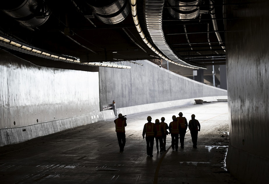 caption: Members of the media walk in the southbound lane on Thursday, November 15, 2018, inside the State Route 99 tunnel in Seattle.