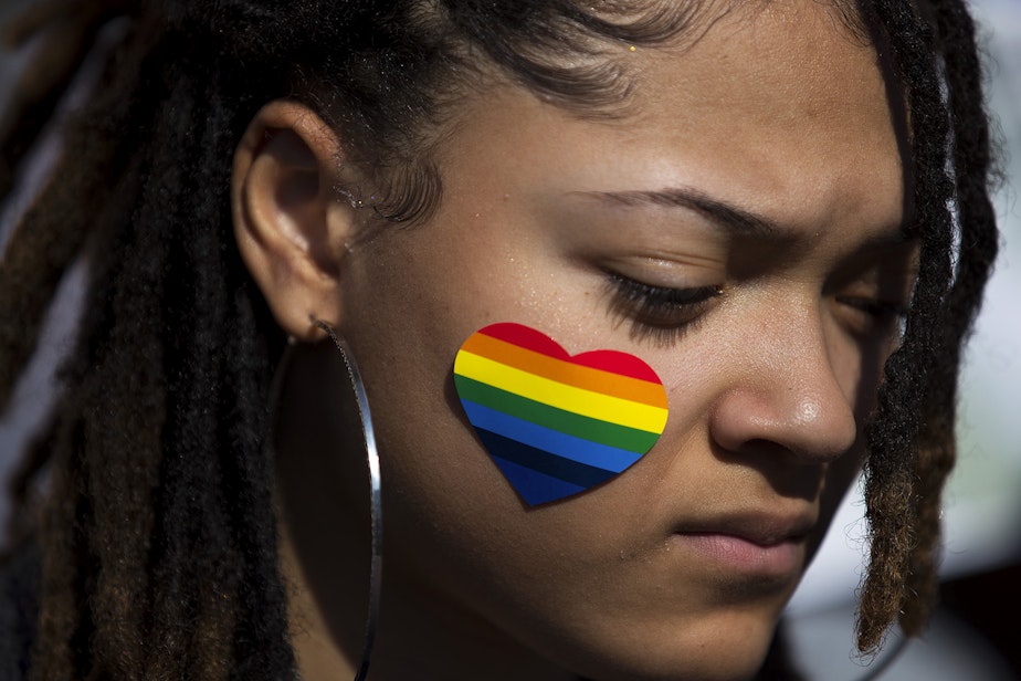 caption: Alex Myers, a junior at Kennedy Catholic High School listens to speakers during a walkout to protest the departure of two LGBT educators on Tuesday, February 18, 2020, in Burien.