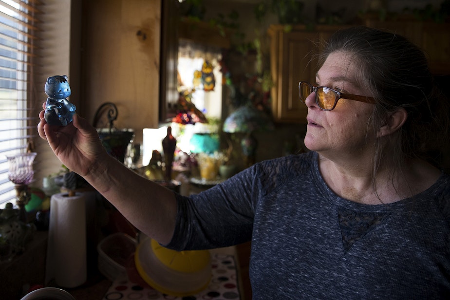 caption: Dagmar Devere holds a Fenton bear up to the light on Tuesday, April 23, 2019, at her home near Pateros, Washington. Devere lost everything, including her home, in the Carlton Complex Fire, and the Fenton bear was the only thing that survived. 