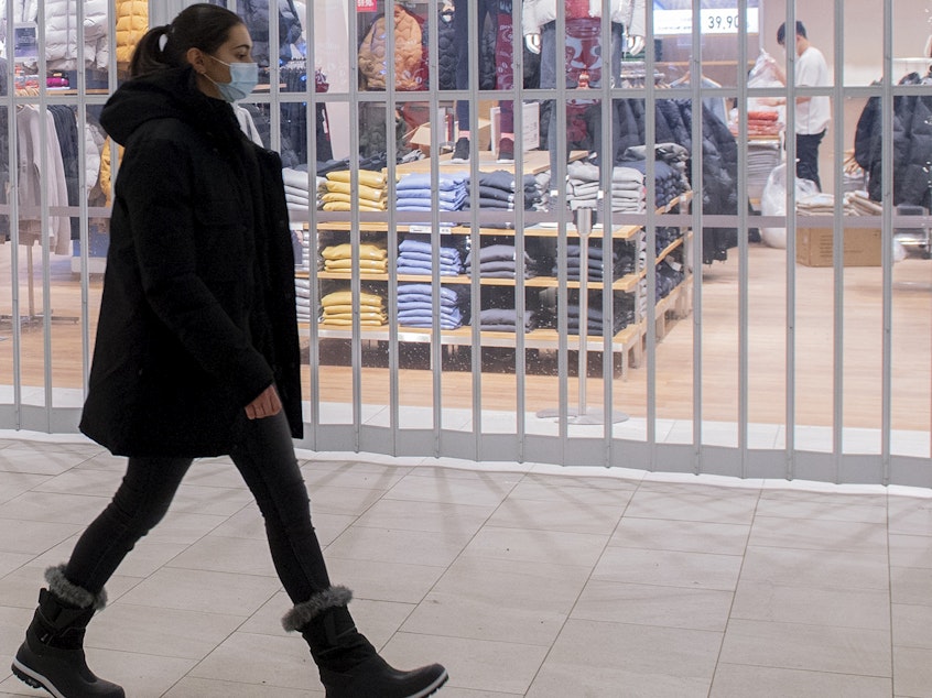 caption: A woman walks by a closed store in a shopping mall in Montreal, Sunday as the COVID-19 pandemic continues in Canada. Some new measures put in place by the Quebec government, including the closure of stores, go into effect today.