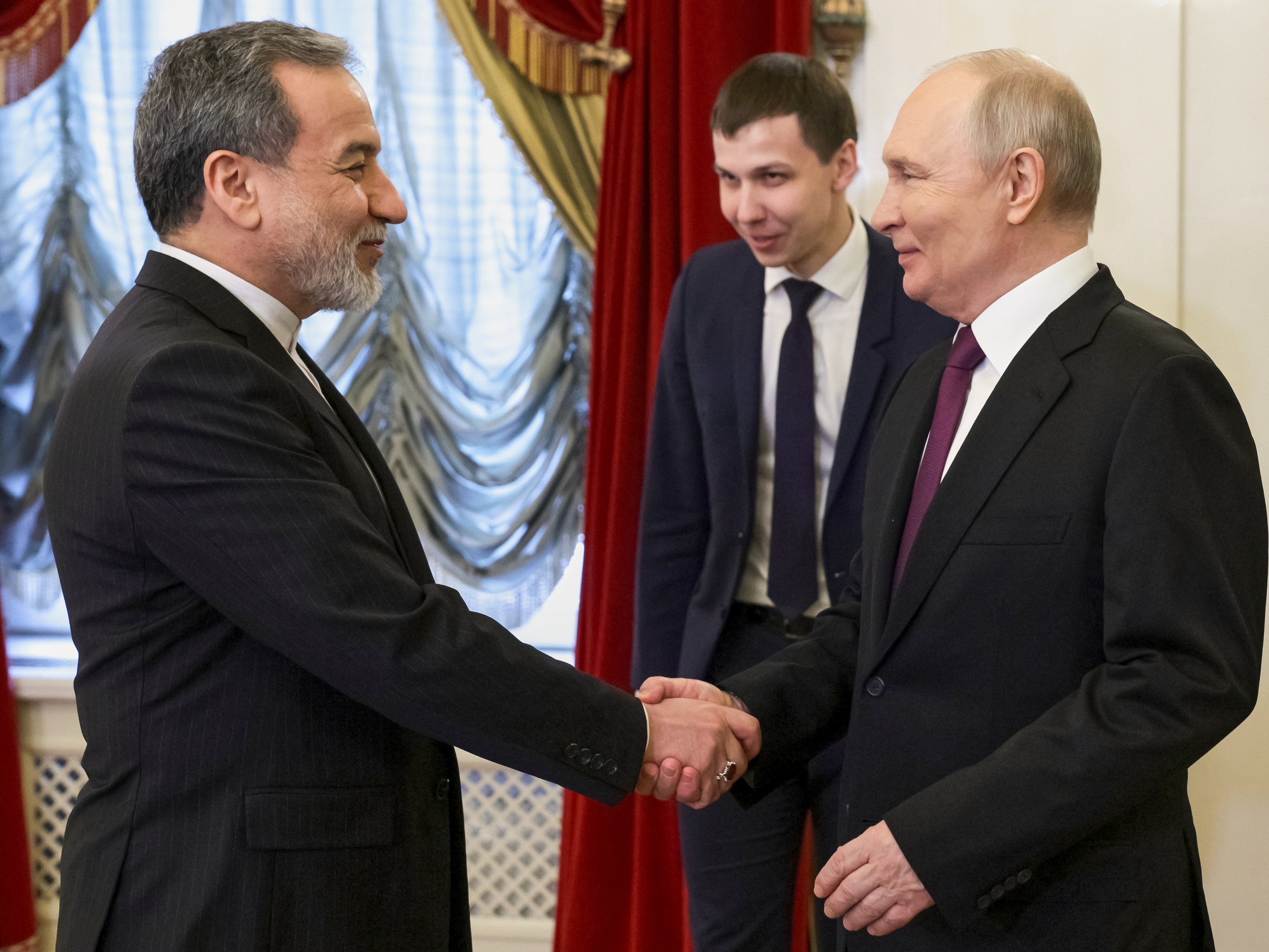 caption: Russian President Vladimir Putin (right) shakes hands with Iranian Foreign Minister Abbas Araghchi during their meeting at the Boris Yeltsin Presidential Library, in St. Petersburg, Russia, Monday.