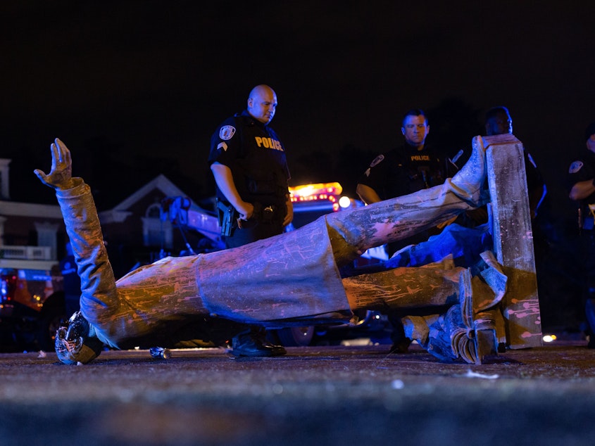 caption: A statue of Confederate States President Jefferson Davis lies on the street after protesters pulled it down in Richmond, Va., on Wednesday.