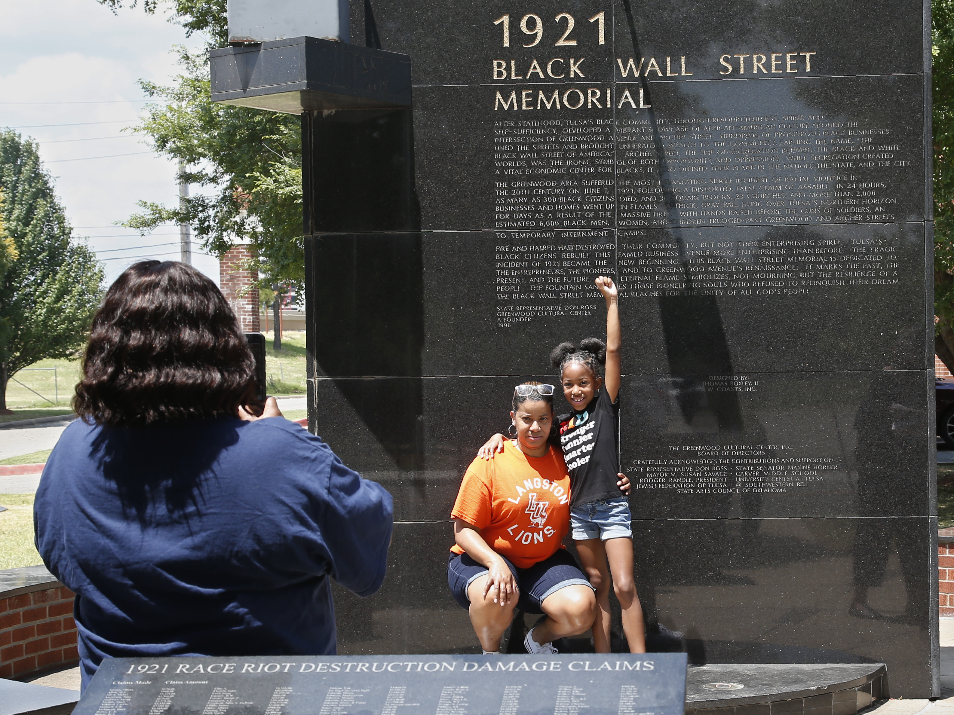 caption: Katrina Cotton, center, of Houston poses for a photo Monday with her daughter, Kennedy Cotton, 7, at the Black Wall Street Memorial in Tulsa, Okla.