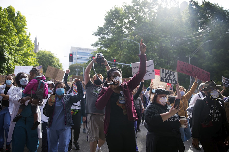 caption: Organizer Dr. Estell Williams, center, leads a crowd of thousands marching in protest to demand justice and an end to police violence, from Harborview Medical Center to Seattle City Hall on Saturday, June 6, 2020, in Seattle.