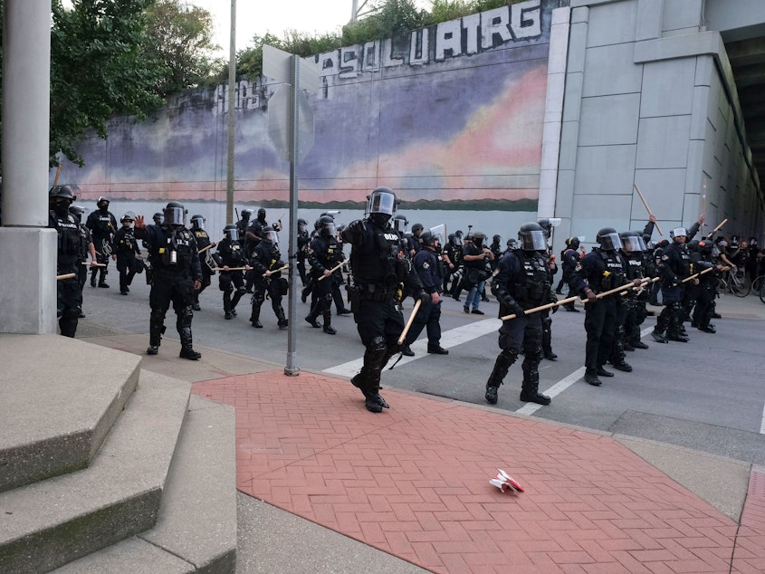 caption: A police line approaches demonstrators in downtown Louisville, Ky., last week during protests over the lack of criminal charges in the police killing of Breonna Taylor and the result of a grand jury inquiry.