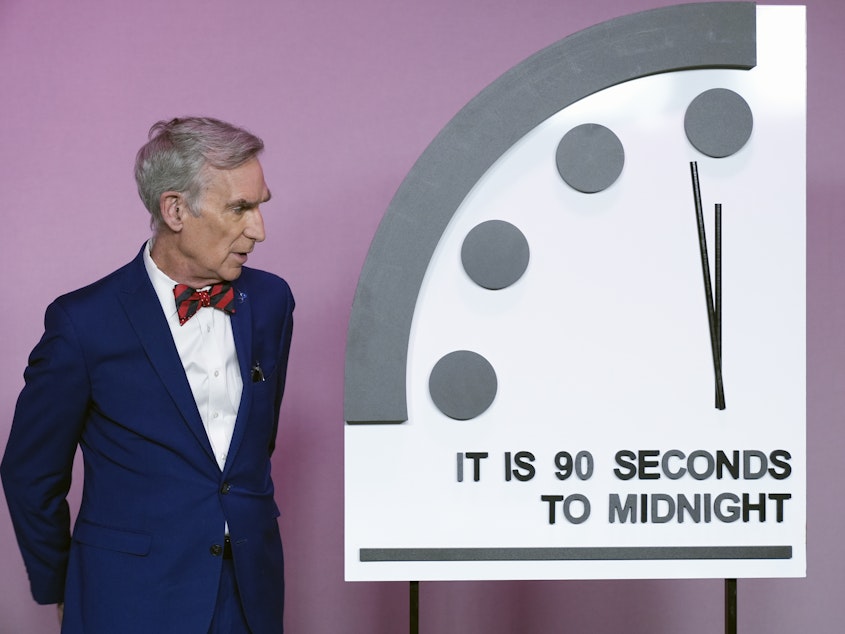 caption: Science educator Bill Nye looks at the "Doomsday Clock," shortly before the Bulletin of the Atomic Scientists announces the latest decision on the "Doomsday Clock" minute hand, Tuesday, Jan. 23, 2024, at the National Press Club Broadcast Center, in Washington.