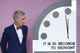 caption: Science educator Bill Nye looks at the "Doomsday Clock," shortly before the Bulletin of the Atomic Scientists announces the latest decision on the "Doomsday Clock" minute hand, Tuesday, Jan. 23, 2024, at the National Press Club Broadcast Center, in Washington.