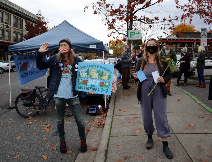 caption: People First Bellingham campaign volunteers Seth Mangold and Sage Jones sought voter support for their coalition's four initiatives at the Bellingham Farmers Market on Saturday.
