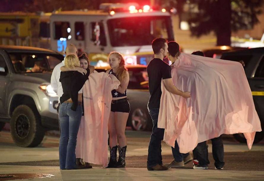 People comfort each other as they stand near the scene Thursday, Nov. 8, 2018, in Thousand Oaks, Calif. where a gunman opened fire Wednesday inside a country dance bar crowded with hundreds of people on "college night," wounding 11 people including a deputy who rushed to the scene.