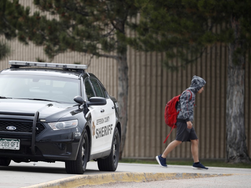 caption: A student leaves Columbine High School late Tuesday in Littleton, Colo. Authorities say they are looking for a woman they say presented a credible threat ahead of the 20th anniversary of the mass shooting there.