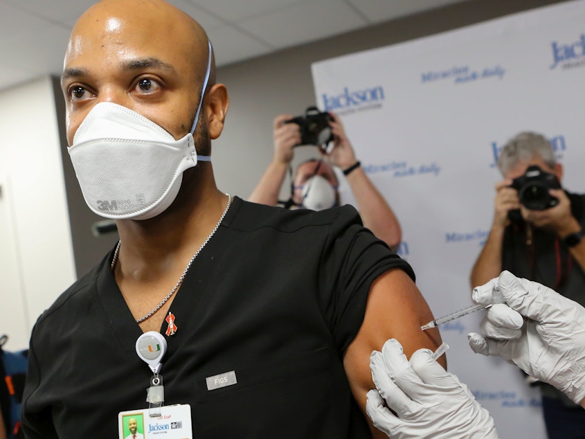 caption: Dr. Hansel Tookes made sure his first dose of Pfizer's COVID-19 vaccine at Jackson Memorial Hospital in Miami on Dec. 15. was televised, as a way to combat hesitancy.