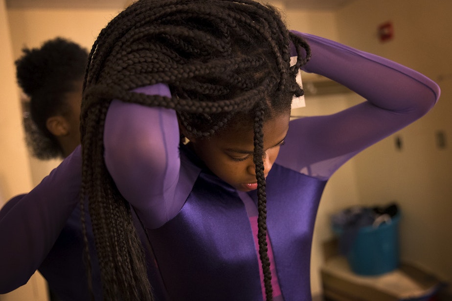 caption: Yizjuani Watson, 11, has help with her costume from Simya Gibson, 13, during a rehearsal on Tuesday, May 15, 2018, at Rainier Beach high school in Seattle.