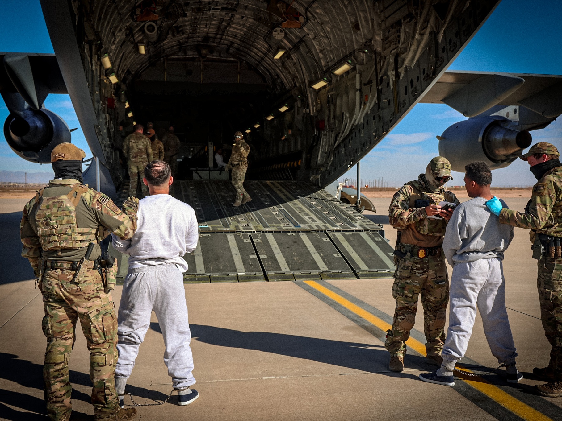 caption: The Department of Homeland Security released photos of migrants as they boarded planes for Guantánamo Bay, Cuba.