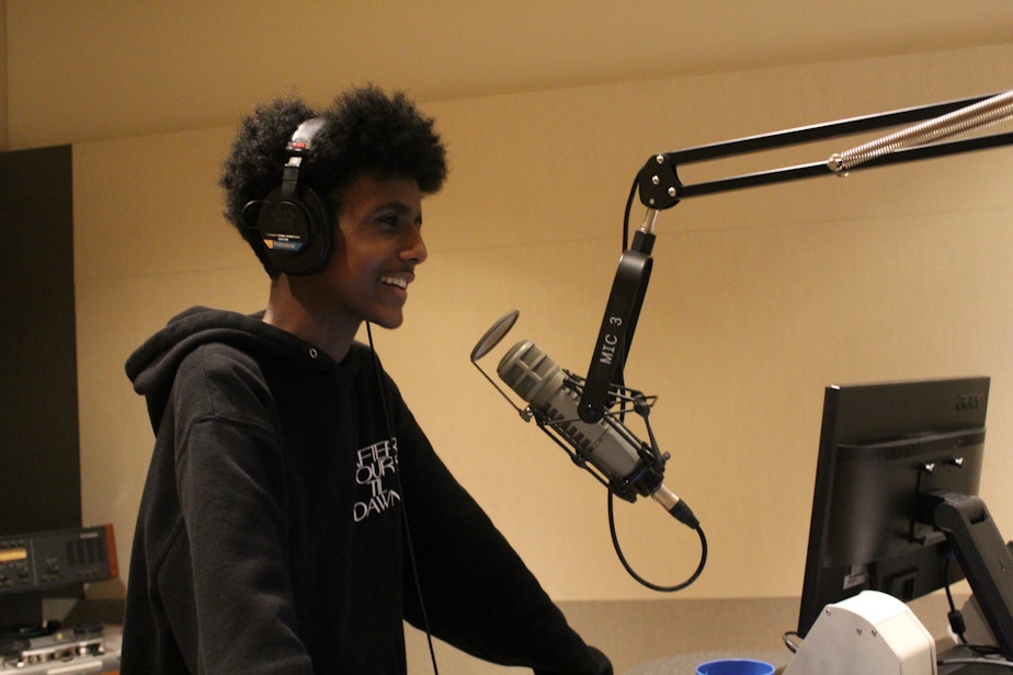 caption: Alex Mengisteab voices his feature story in a KUOW studio.