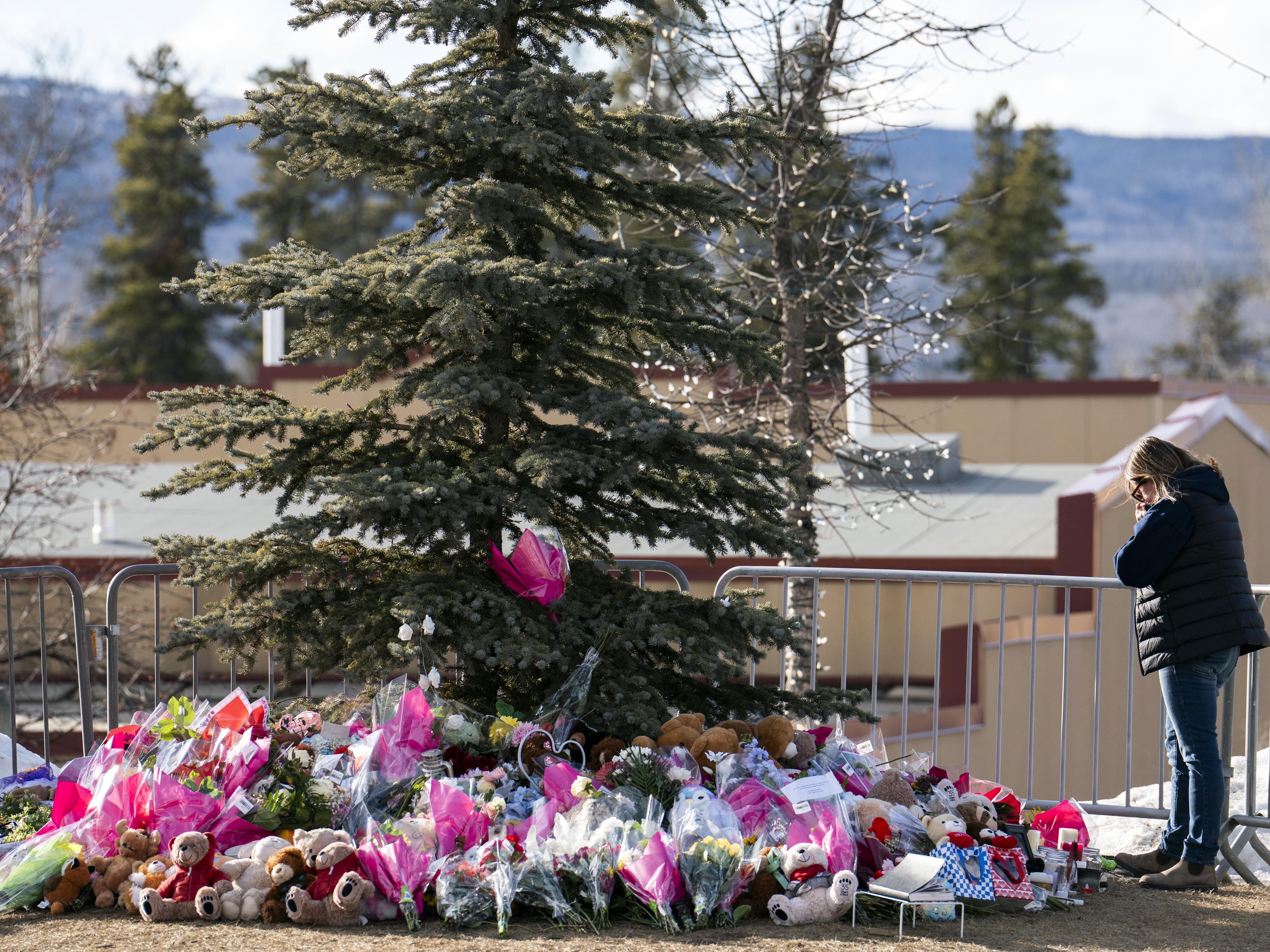 caption: A woman mourns at a makeshift memorial for the victims of a deadly mass shooting that took place in the town of Tumbler Ridge, British Columbia. A lawsuit filed Wednesday claims that OpenAI was negligent for failing to report the shooter to authorities after her account was flagged for "gun violence activity and planning."