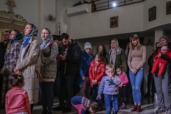 caption: People who fled the war in Ukraine and members of the Ukrainian diaspora pray in an Orthodox church in Krakow on Sunday.