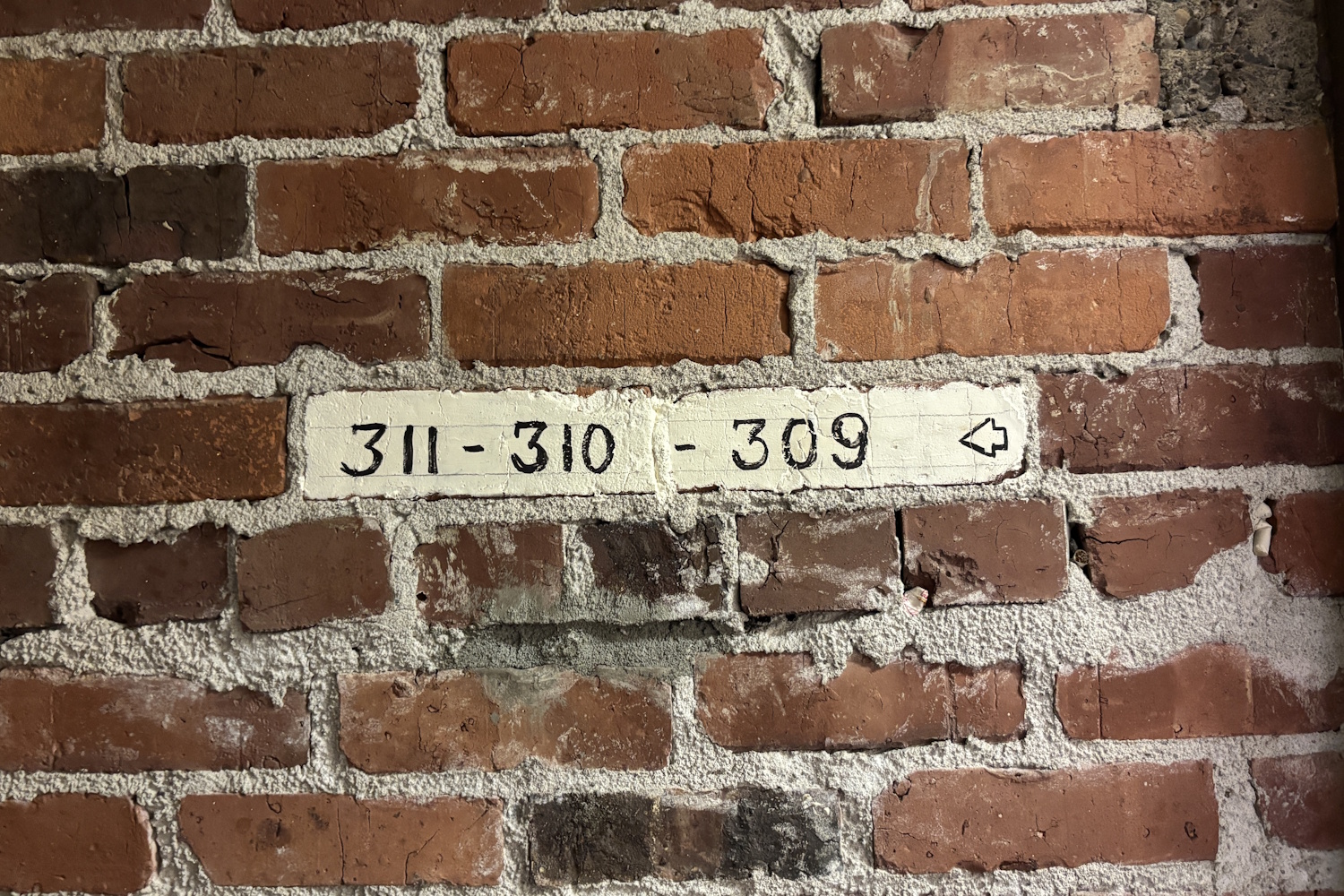 caption: An apartment number painted on an unreinforced masonry wall at a historic apartment building in Seattle's Chinatown International District.