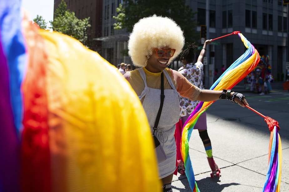 caption: Jemyka Travis, 31, left, roller-skates with Von Tele, 33, with T-Mobile’s float during the Seattle Pride Parade on Sunday, June 25, 2023, in downtown Seattle. 